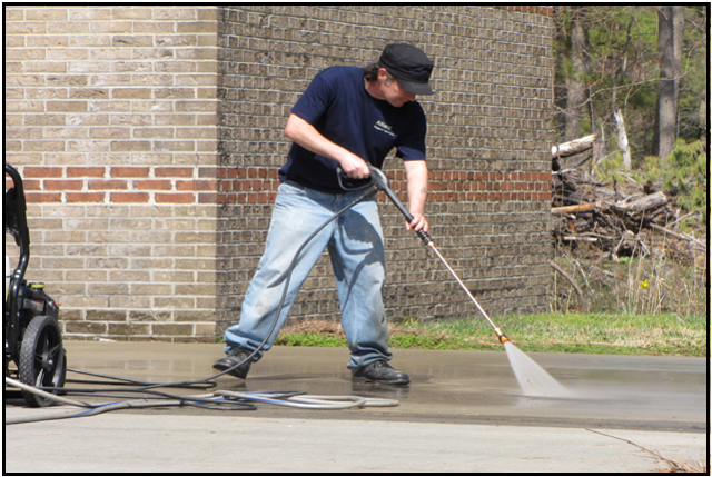 Alliant crew member pressure washing a concrete walkway
